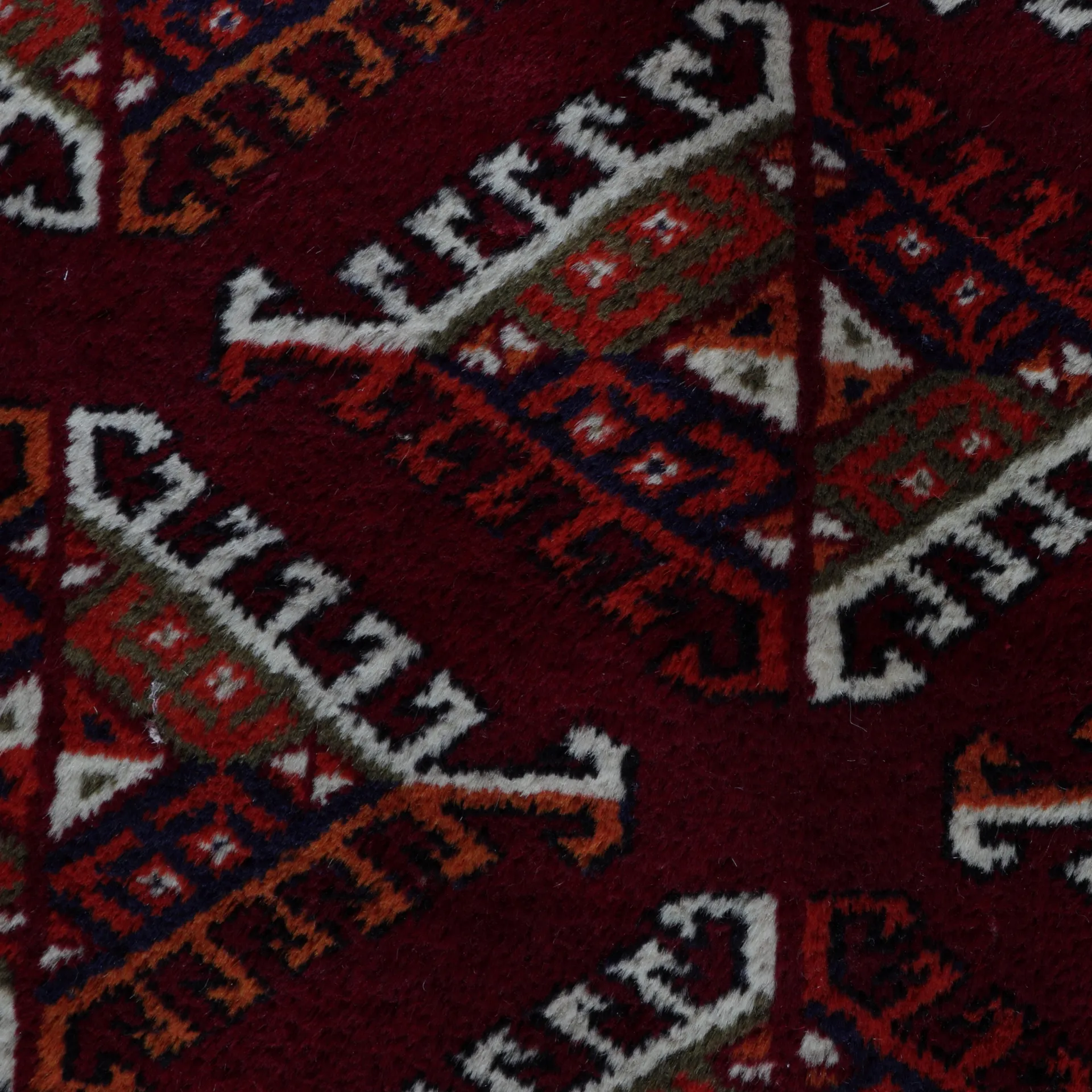 Russischer Yomut, handgeknüpft aus Schurwolle, reichliche Ornamentierung des  Mittelfeldes und der Bordüren, rotgrundig/weiß/mehrfarbig, Detailansicht                                         